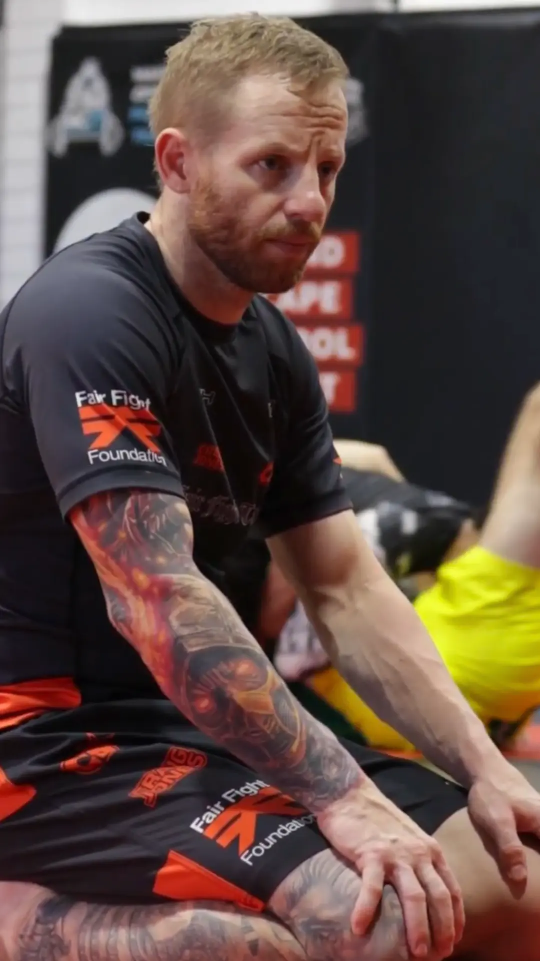 Coach sitting on the mats watching the class