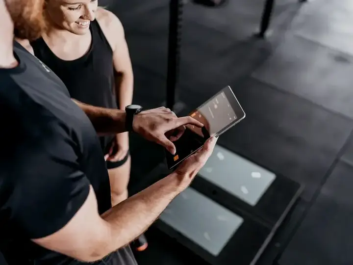 A coach reviewing performance testing data on a tablet with an athlete
